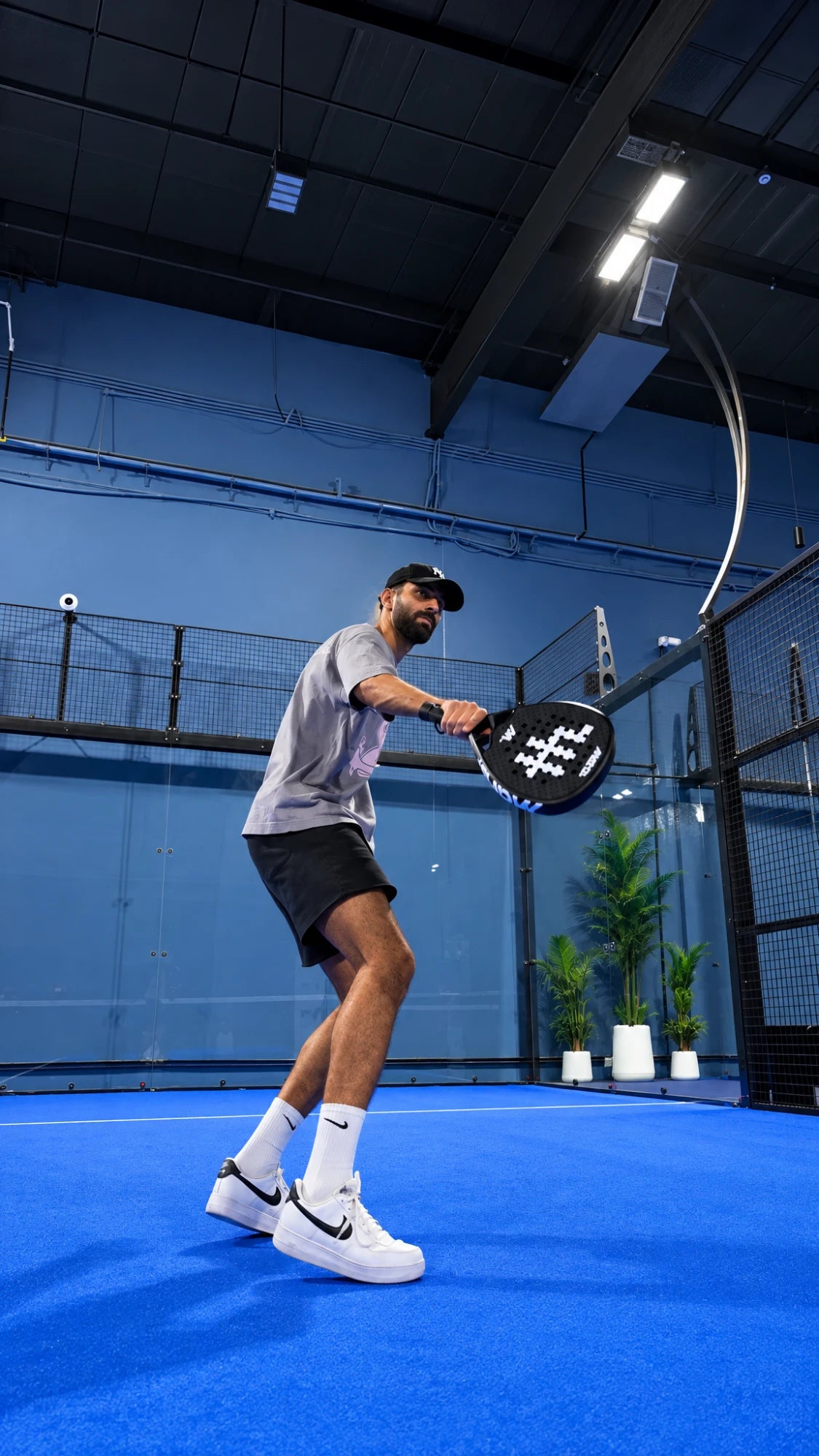Player ready to hit with the MDRB Dark Matter padel racket on an indoor padel court