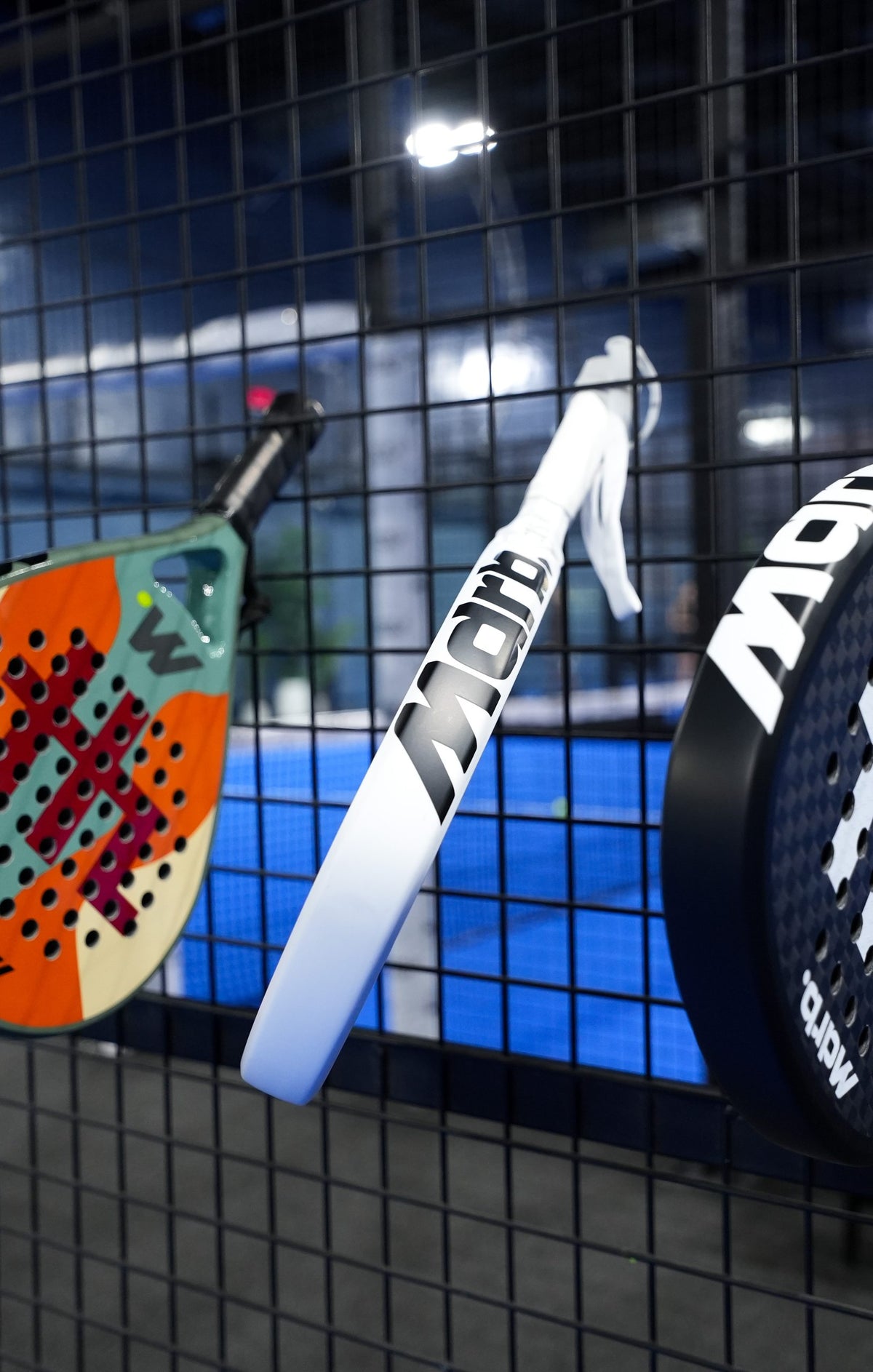 MDRB Camel Edition and Vellum Ghost padel rackets hanging on the fence