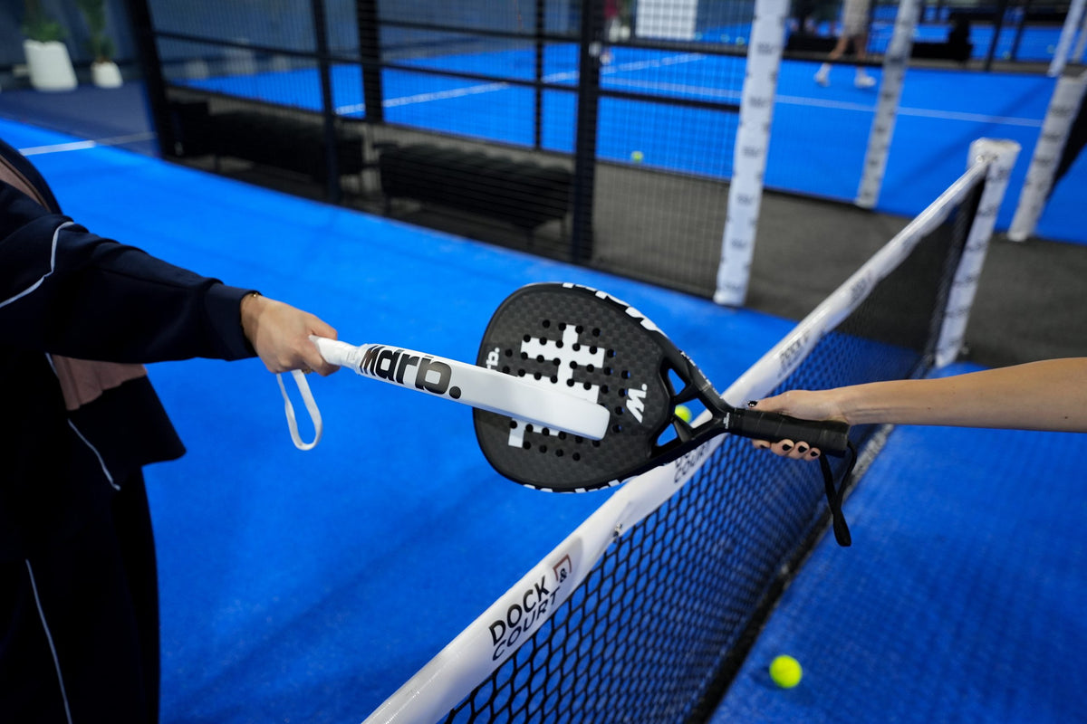 Two players passing the MDRB Dark Matter padel racket over the net