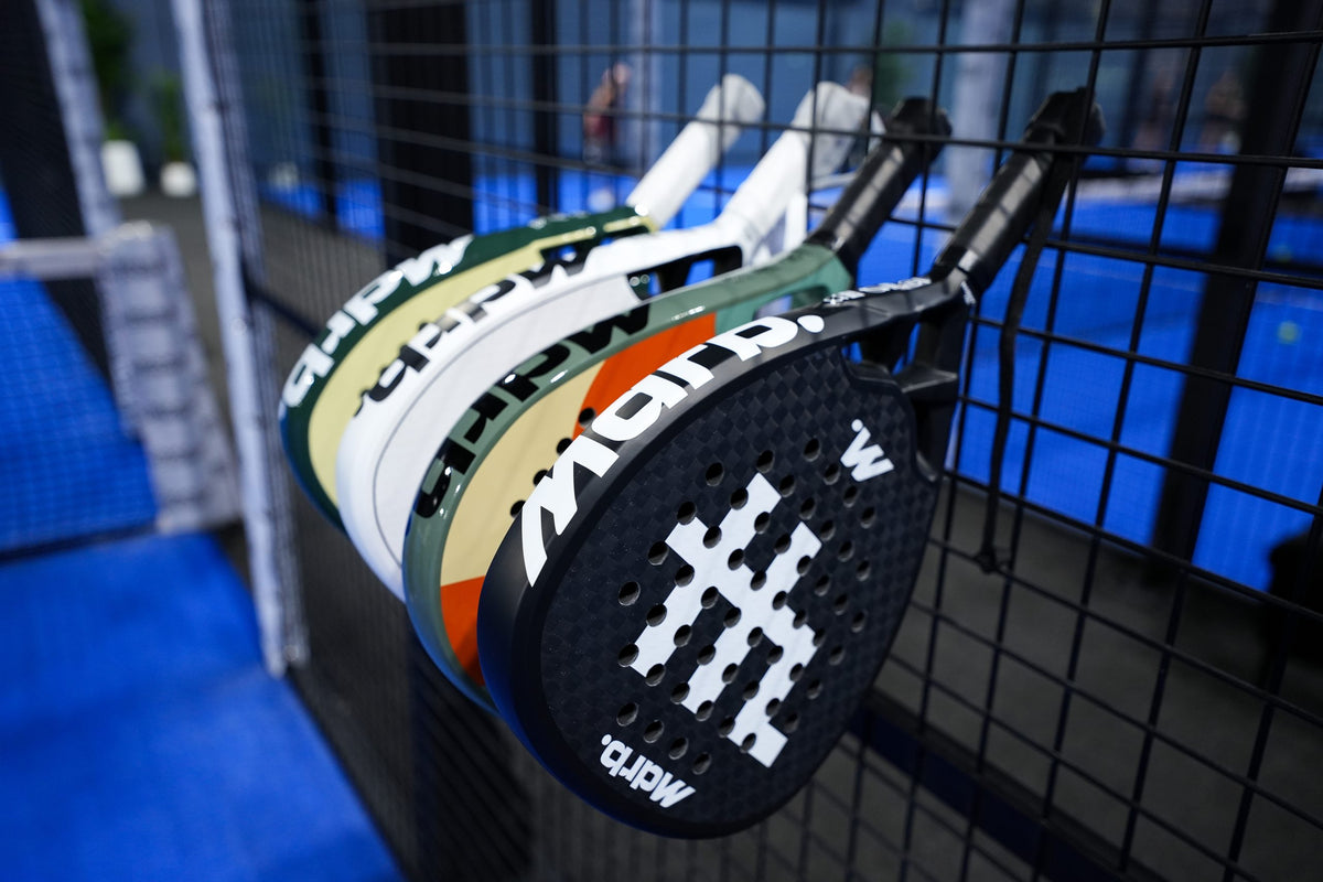 MDRB padel rackets stacked on the fence with the Dark Matter in front