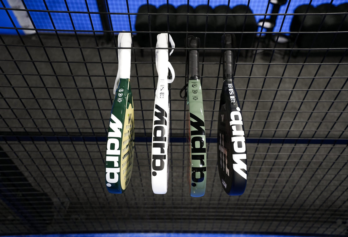 MDRB padel rackets hanging on the court fence