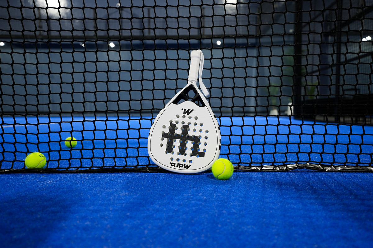 MDRB Vellum Ghost padel racket resting against the net on a blue padel court
